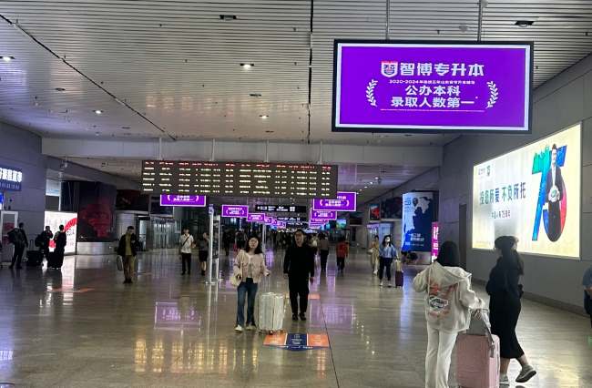 青岛北站出站通道上方联排大屏广告出站客流人来人往 