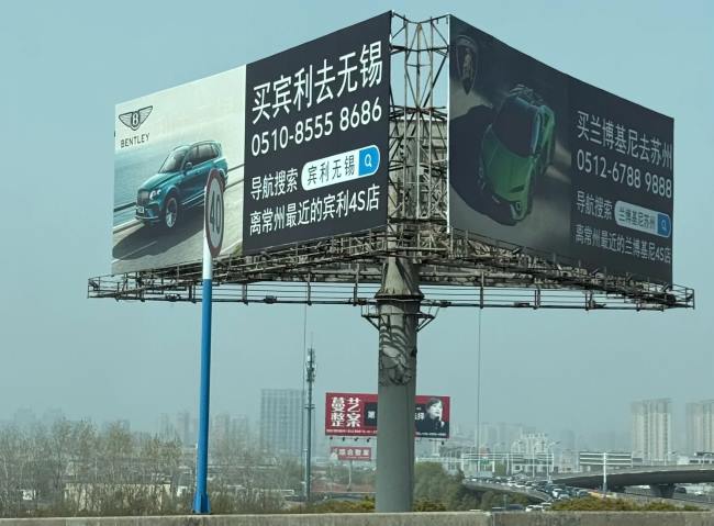 常州境内的高速立柱大牌广告刊登着买宾利去无锡买兰博基尼去苏州