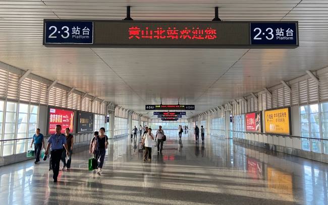 黄山北站2层进站天桥两侧分别是本地品牌臭鳜鱼、全江腊味、新安源有机茶以及徽商银行的广告
