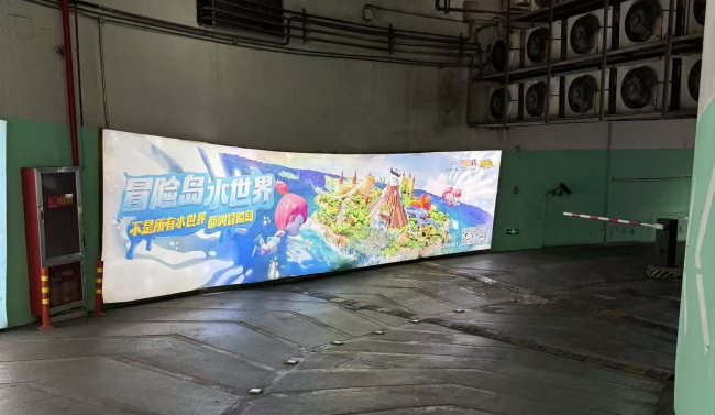 义乌之心地下停车场墙面灯箱刊登着丽水冒险岛水世界的文旅广告画面