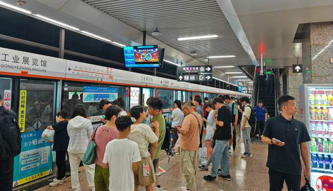 沈阳地铁播音广告回荡在工业展览馆站台层候车区，覆盖乘车与下车乘客