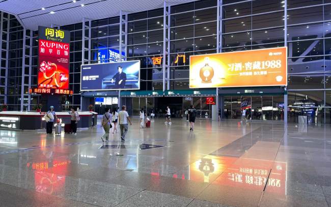 广州南站1层到达出口服务台夜间场景实拍图，图为广州南站由内向外拍摄西门出口场景