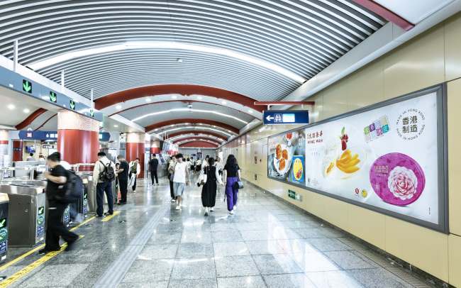北京地铁王府井站站厅层闸机如入口旁墙面，2026中秋国庆前夕刊登着香港元郎荣华月饼大幅灯箱广告