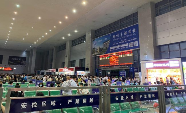 图为2023年实景拍摄的郴州西站候车大厅场景图，丰祺学校选择中央大型广告牌 