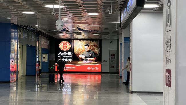 图为深圳机场与地铁站接驳的升降梯等候区实拍图，周围墙面是八合里牛肉火锅广告画面