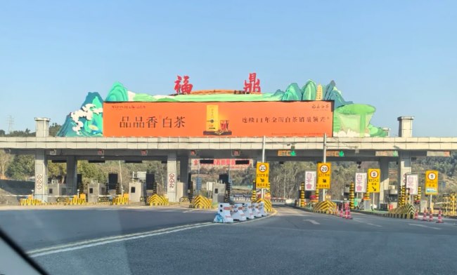 图为驾乘人员视角在车上拍摄的福鼎收费站视角，站顶灯箱广告牌是品品香白茶